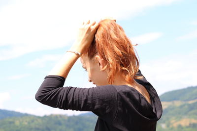 Woman with arms raised standing against sky