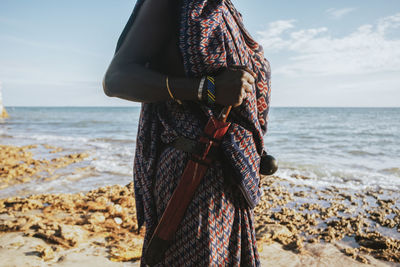 Woman standing at beach against sky