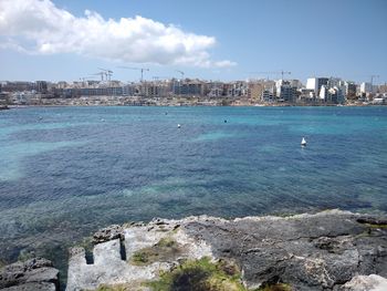 Scenic view of sea by buildings against sky