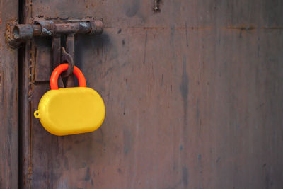 Close-up of yellow padlock toy hanging on metal sheet wall