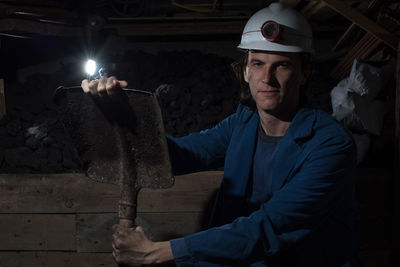 Portrait of manual worker holding shovel at construction site during night