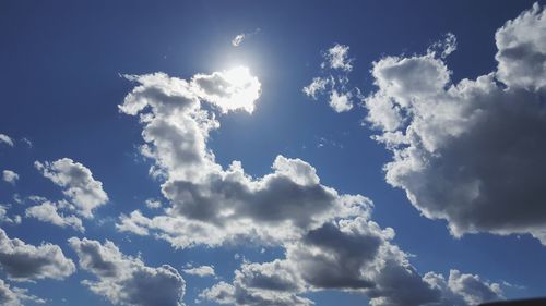 Low angle view of sunlight streaming through clouds