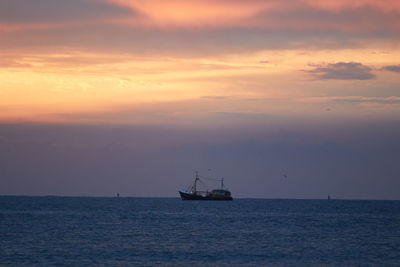 Sailboat sailing on sea against sky during sunset