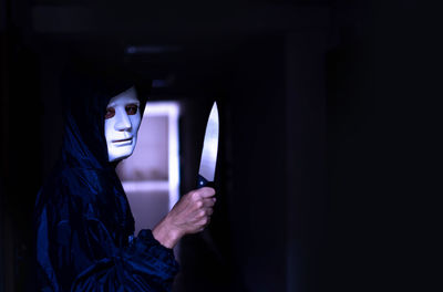 Close-up portrait of woman holding mirror in the dark