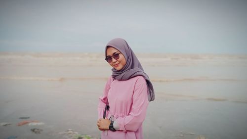 Portrait of young woman standing at beach