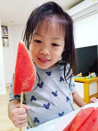 Smiling girl holding watermelon slice at home