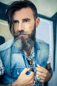 Close-up of hipster wearing denim jacket against wall