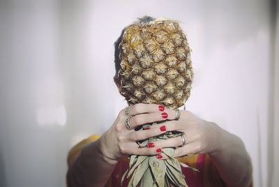 Woman holding pineapple in front of face