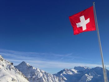 Low angle view of swiss flag against blue sky