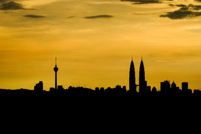 Silhouette petronas tower and kuala lumpur tower against orange sky