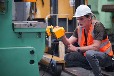 Side view of man using mobile phone while sitting in gym