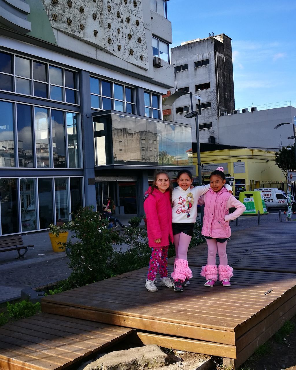 building exterior, architecture, built structure, full length, real people, girls, childhood, togetherness, day, looking at camera, outdoors, lifestyles, wood - material, leisure activity, happiness, pink color, smiling, sky, young adult, people