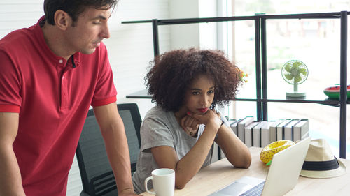 Young couple looking away while sitting on table