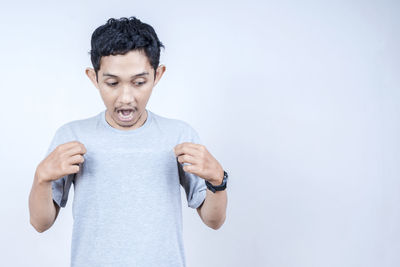 Portrait of young man standing against white background