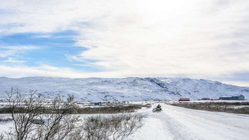 Road by snow covered mountain against sky