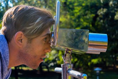 Close-up of a man looking through binoculars outdoors