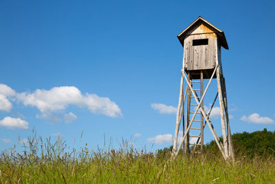 Hunting blind with a blue sky's in the back standing  in the middle of a field 