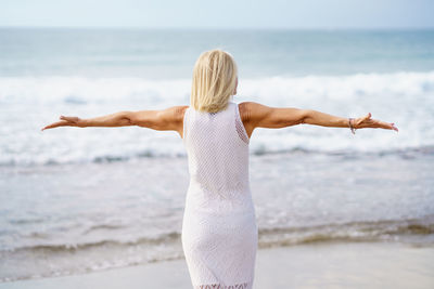 Rear view of woman standing at beach