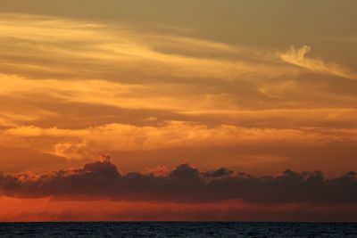 Scenic view of sea against dramatic sky during sunset