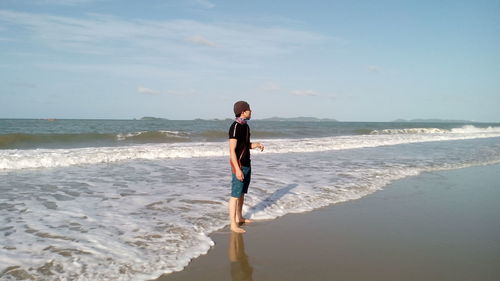 Rear view of woman on beach against sky