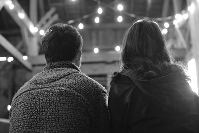 Rear view of couple sitting in illuminated patio at night