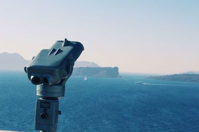 Close-up of camera against sea against clear sky