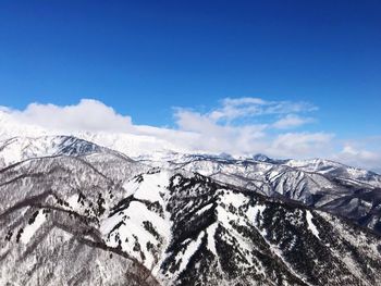 Scenic view of snowcapped mountains against blue sky