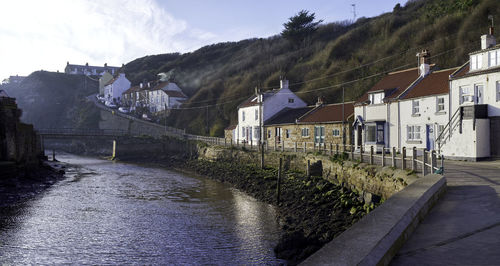 Houses by river in town against sky