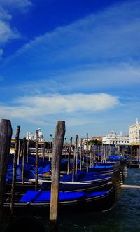 Boats moored at harbor against blue sky