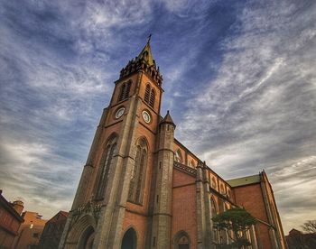 Low angle view of clock tower against cloudy sky