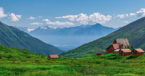 Houses on field by mountains against sky