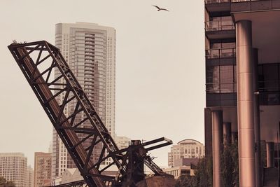 Bascule bridge by modern buildings against clear sky