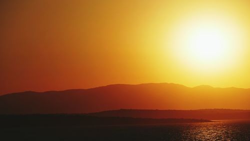 Evening view of bright orange sunset over mountains and sea