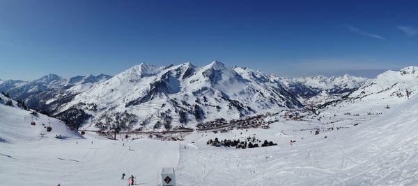 Panoramic shot of snow covered mountains against clear blue sky