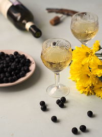 Autumn still life with yellow hresanthem flowers, dry white wine and dark blackthorn berries. 