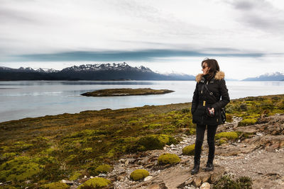 Young woman standing on rock at mountain by river at patagonia