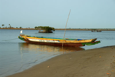 Sailboat moored on sea against clear sky