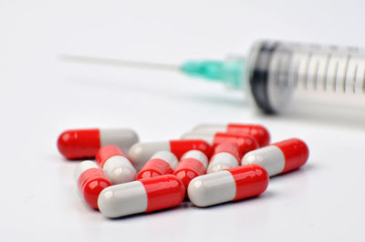 Close-up of capsules with syringe on white background