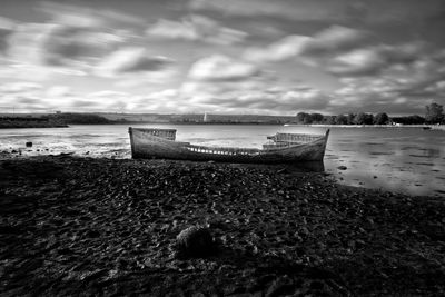 Boat moored on beach against sky