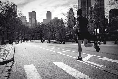 Full length rear view of man jogging on street in city