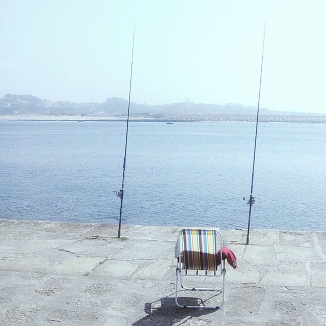 water, sea, empty, tranquility, chair, absence, tranquil scene, bench, clear sky, scenics, mountain, relaxation, nature, beauty in nature, beach, copy space, sky, horizon over water, jetty, day