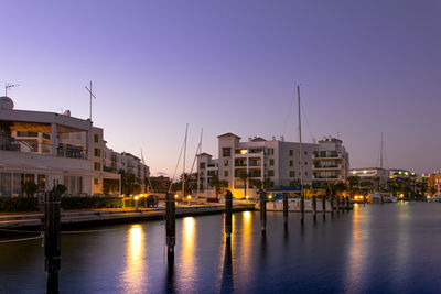 Sailboats moored on river by buildings against sky in city