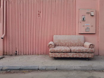 View of abandoned sofa on street against wall