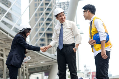 Engineers shaking hands with man in city