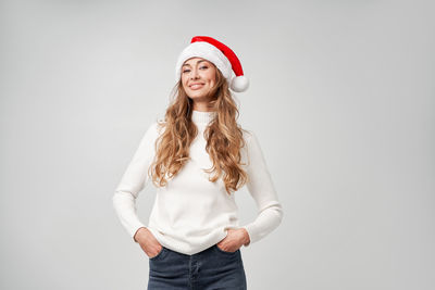 Portrait of smiling young woman standing against white background