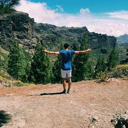 Rear view of man standing on mountain against sky