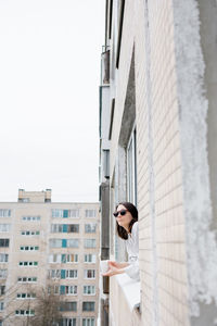 Woman wearing sunglasses looking out through window