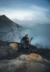 Woman sitting on rock against mountains