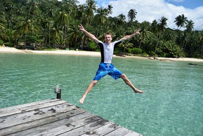 Full length of a man jumping on pier over lake