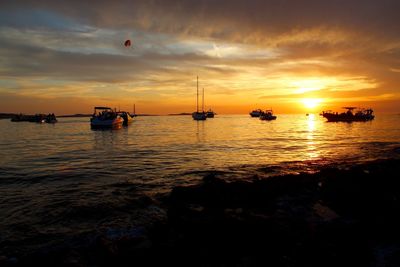 Silhouette boats sailing in sea against sky during sunset